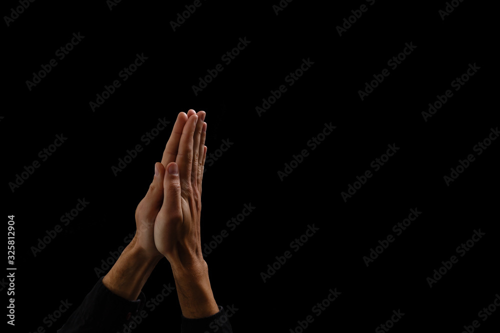 Fototapeta premium Handsome man sit prayer on black background. His hands are praying for God's blessings.