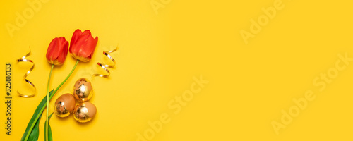 Gold brown Easter eggs with red tulps on yellow background photo