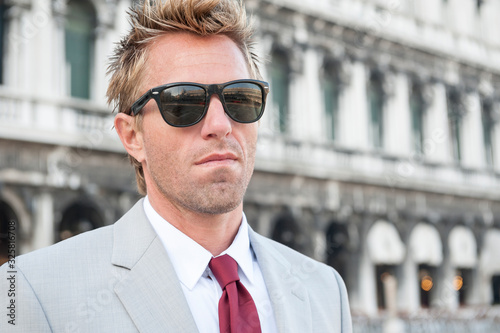 European businessman with disheveled hair standing in front of classic Italian architecture in Venice, Italy