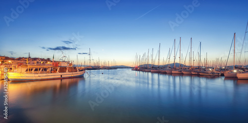 Night view of the Alghero Marina yacht port at the Gulf of Alghero with anchored sailboats