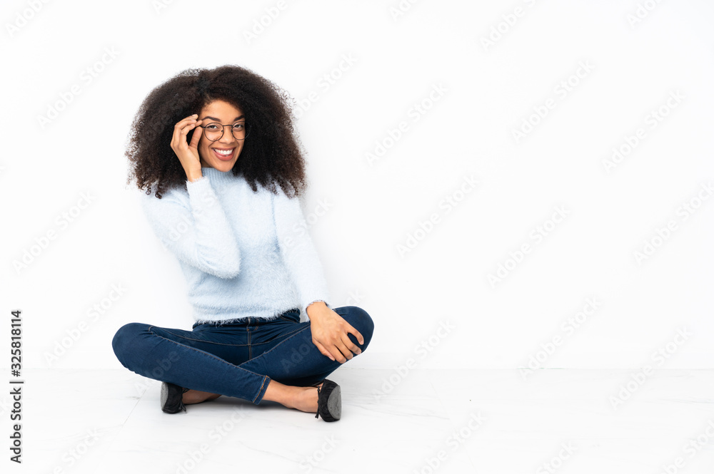 Young african american woman sitting on the floor with glasses and happy Young african american woman sitting on the floor with glasses and happy