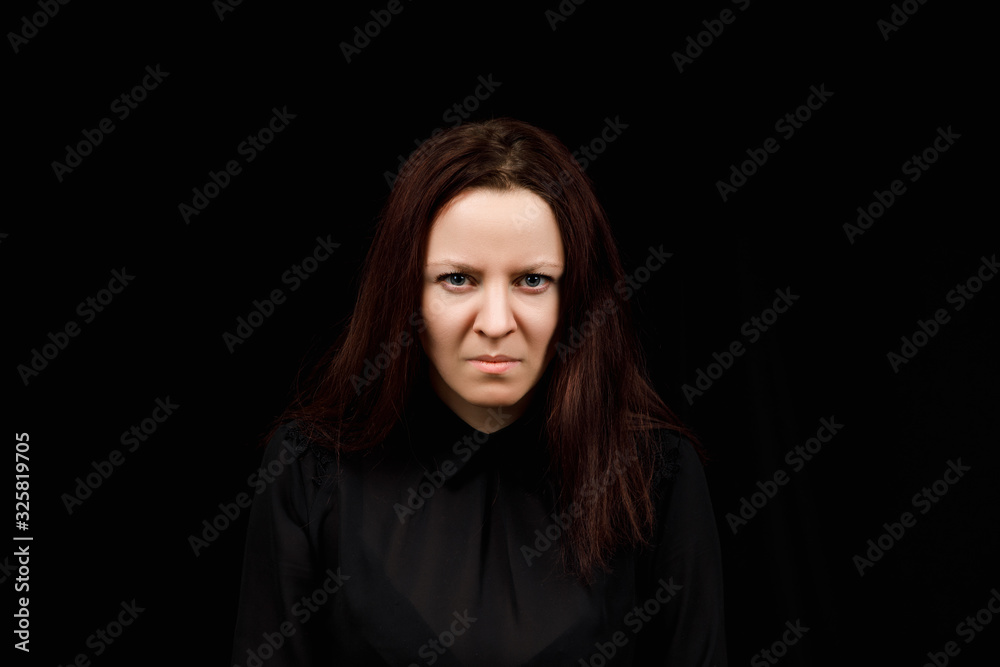 Middle age woman is angry. The girl wear casual sweeter on a black background. Evil woman, hands on her sides