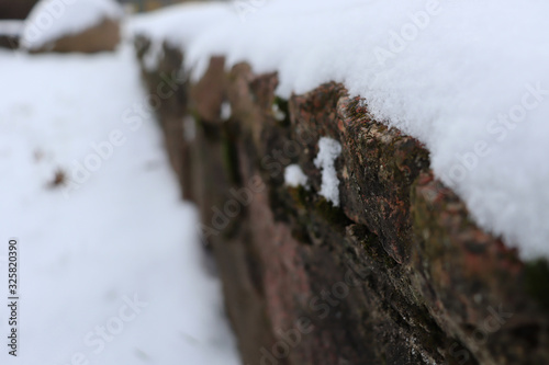 Background of a stone fence covered with snow. Beautiful fence with snow