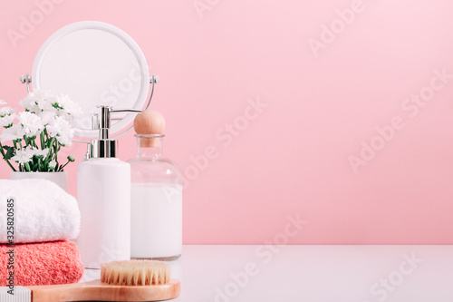 Soft light pink bathroom decor  design  set of cosmetic bottles  mirror  towel  soap dispenser. Cosmetic accessories on shelf bathroom.