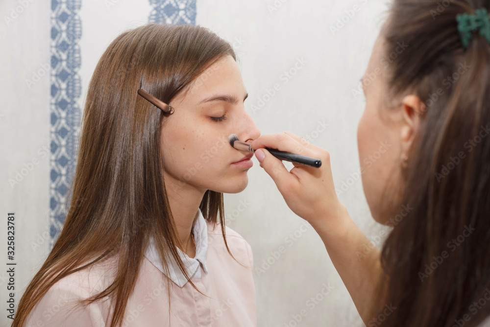 The process of creating makeup. Makeup artist working with a brush on the face of the model. The process of creating makeup. Makeup artist working with a brush on the face of the model.