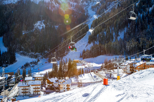 View of Arabba village and chair lift with skiers on a sunny winter day. Sellaronda, Dolomiti Superski. photo