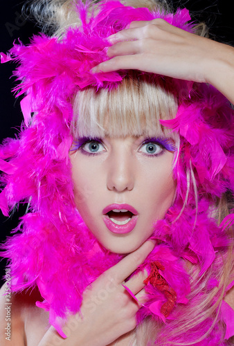 Portrait of young sensual female with pink feathers. Lovely woman with light skin and sweet smile. Studio photo shoot. 