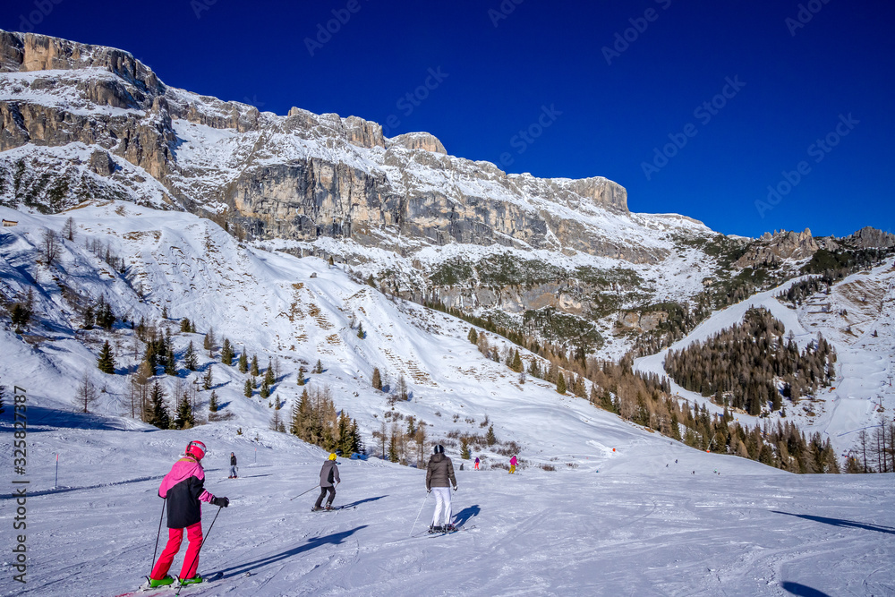 View of Arabba ski resort. Skiers on the red ski run. Sellaronda, Dolomiti Superski. View of Arabba ski resort. Skiers on the red ski run. Sellaronda, Dolomiti Superski.