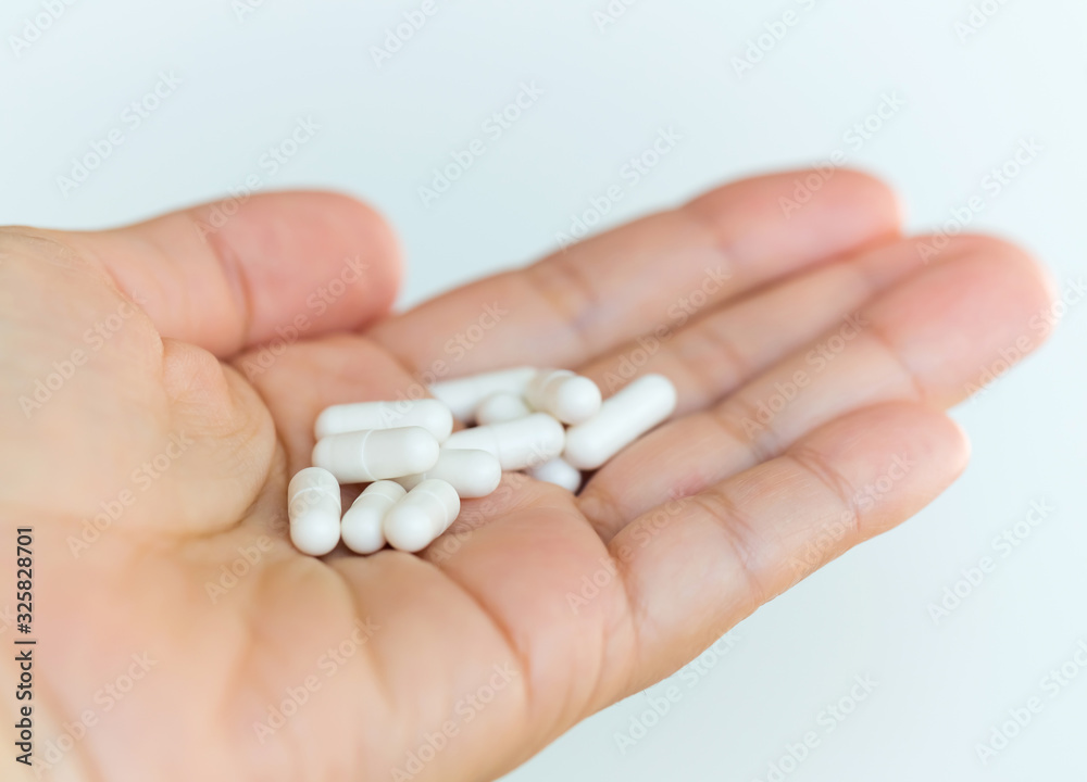 Medical composition. A handful of drugs in the palm of hand. White capsules on a human hand. Medical background with free space for text Medical composition. A handful of drugs in the palm of hand. White capsules on a human hand. Medical background with free space for text