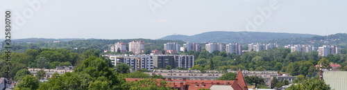 view of the modern city on the hills, stone buildings. different style houses in the distance. city with lots of greenery, tall trees © Alexkarankevich