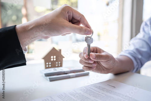 Sale purchase contract to buy a house, Real estate agent are presenting home loan and giving keys to customer after signing contract to buy house with approved property application form