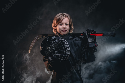 Photography Young blonde sporty boy, ice hockey player, posing in a dark studio for a photos