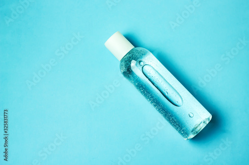 Transparent cosmetic bottle on a blue background, copy space, top view. The concept of skin care, natural cosmetics.