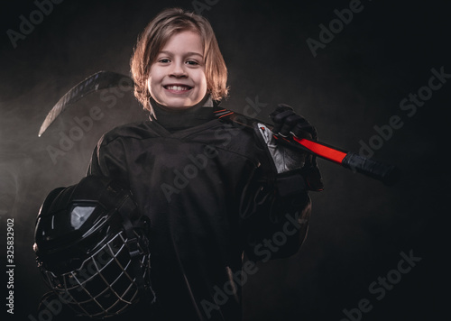 Photography Young blonde sporty boy, ice hockey player, posing in a dark studio for a photos