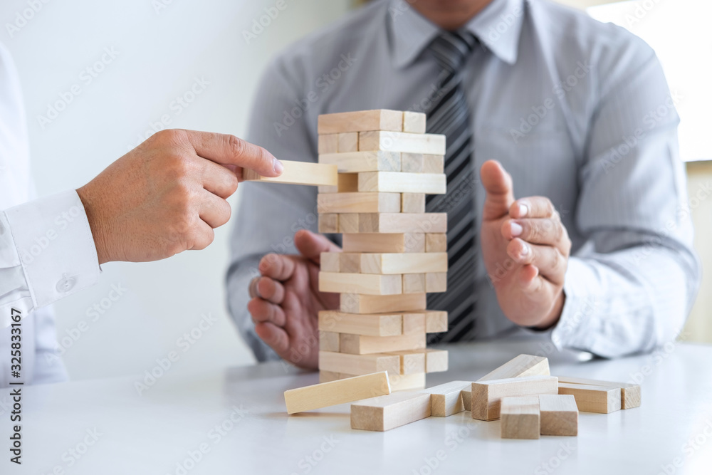 Planning Risk and Strategy in Business, Image of two Businessman hand placing making wooden block structure growing up the tower and protection to planning and development to successful Planning Risk and Strategy in Business, Image of two Businessman hand placing making wooden block structure growing up the tower and protection to planning and development to successful