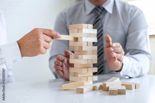 Planning Risk and Strategy in Business, Image of two Businessman hand placing making wooden block structure growing up the tower and protection to planning and development to successful