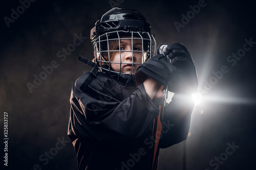 Canvas Print Young blonde sporty boy, ice hockey player, posing in a dark studio for a photos