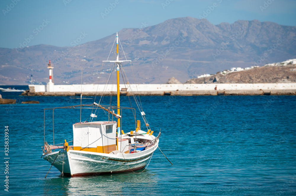 Traditional Greek boat moored in a calm Mediterranean harbor in Mykonos, Greece