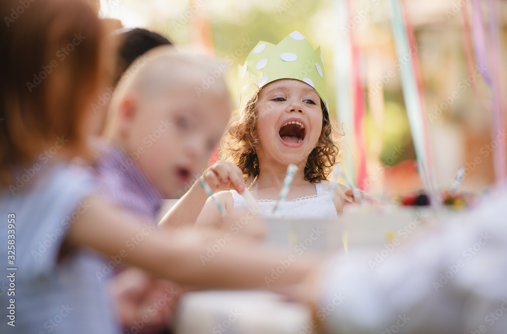 Small children sitting at the table outdoors on garden party in summer. Small children sitting at the table outdoors on garden party in summer.