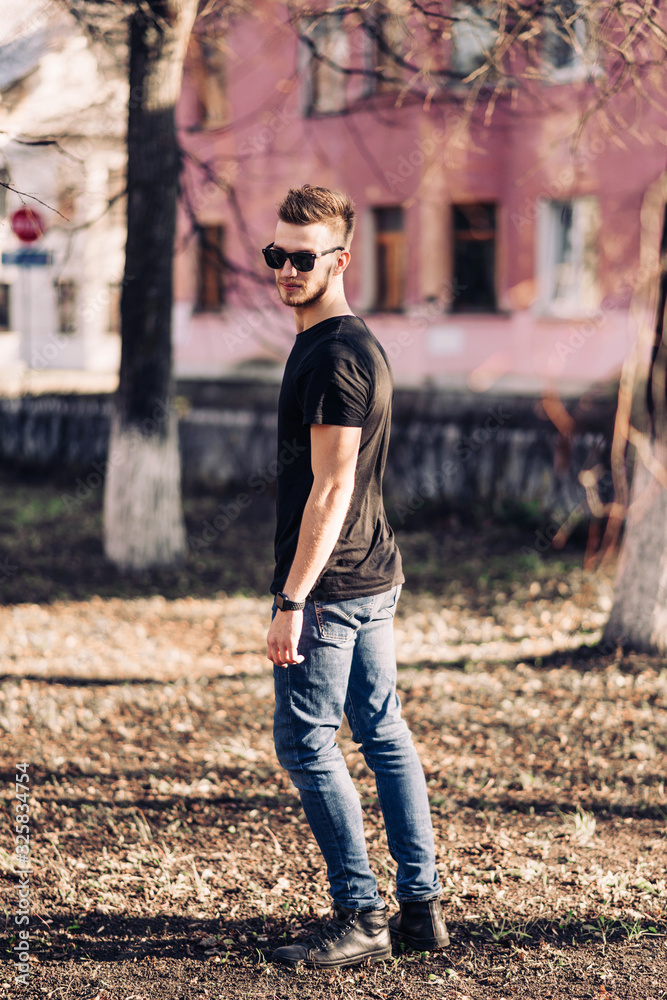 Handsome young man with a beard and stylish haircut in sunglasses in fashionable clothes. Street Lifestyle. Handsome young man with a beard and stylish haircut in sunglasses in fashionable clothes. Street Lifestyle.