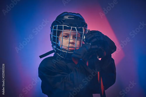 Canvas Print Young blonde fit boy, ice hockey player, posing in a bright neon studio for a ph