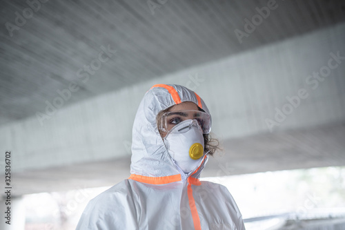 Woman with protective suit and respirator standing outdoors, coronavirus concept.