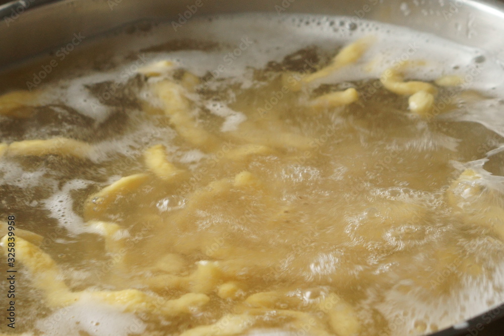 a pile of homemade swabian spaetzle pasta noodles cook in a pot in hot water a pile of homemade swabian spaetzle pasta noodles cook in a pot in hot water