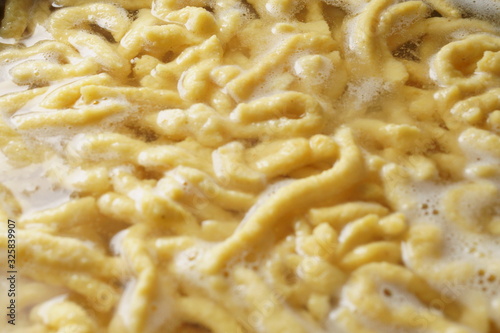 a pile of homemade swabian spaetzle pasta noodles cook in a pot in hot water