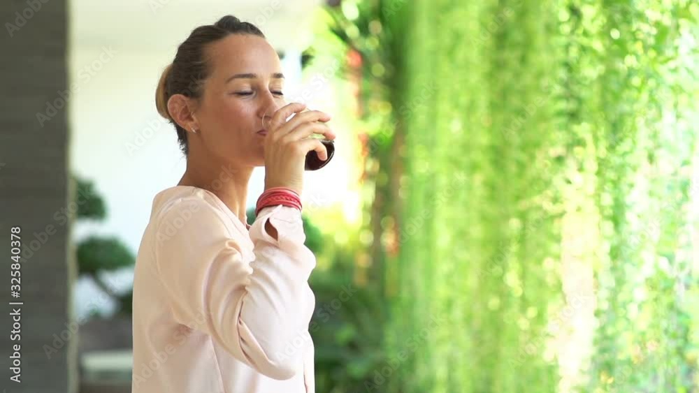 Happy pretty woman drinking juice in garden at home, slow motion Happy pretty woman drinking juice in garden at home, slow motion
