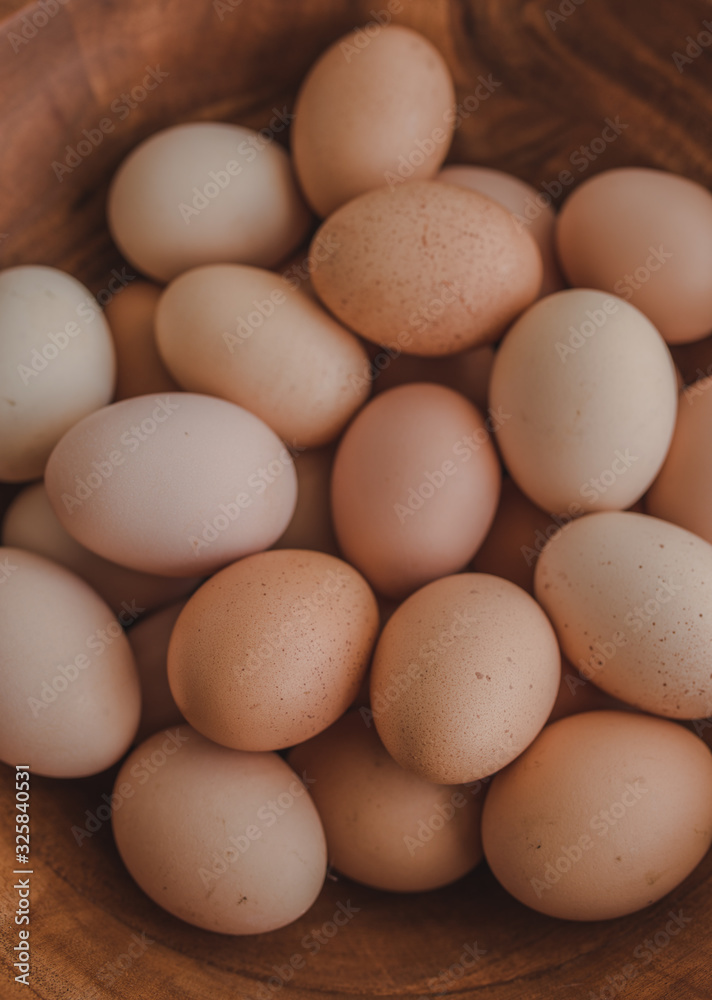 A lot of organic eggs in a large wooden bowl. Chickens eggs from ecologically clean areas. Eggs of different colors. Easter concept. Top view. A lot of organic eggs in a large wooden bowl. Chickens eggs from ecologically clean areas. Eggs of different colors. Easter concept. Top view.