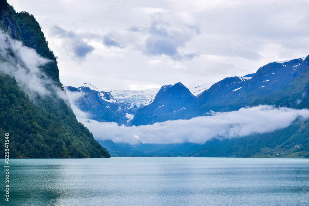 Landscape of beautiful Oldevatnet glacial lake and foggy mountains in which there are glaciers of Jostedalsbreen National Park. Norway.