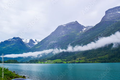 Landscape of beautiful Oldevatnet glacial lake and foggy mountains in which there are glaciers of Jostedalsbreen National Park. Norway.