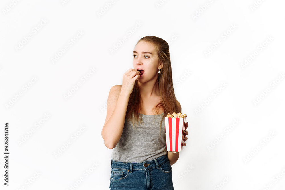 Beautiful blonde girl eat popcorn and watch movie isolated on white background. Copy Space, template for blog and advertising. Woman hold pop corn and watch in right Beautiful blonde girl eat popcorn and watch movie isolated on white background. Copy Space, template for blog and advertising. Woman hold pop corn and watch in right
