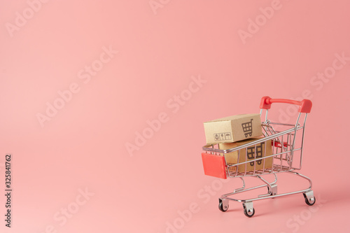 Shopping concept : Cartons or Paper boxes in red shopping cart on pink background. online shopping consumers can shop from home and delivery service. with copy space