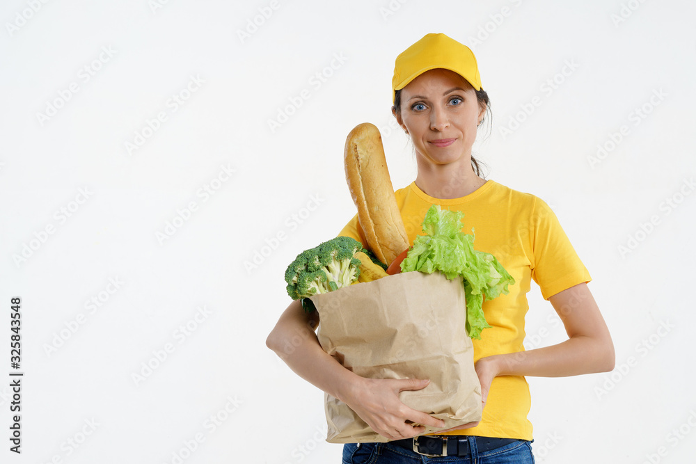 Smiley delivery woman in yellow posing with grocery bag, white background Smiley delivery woman in yellow posing with grocery bag, white background