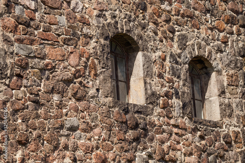 There are two Windows in the old stone wall