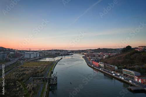 Damatic evening landscape Picture of river Nervion delta to biscayne bay in Bilbao, biggest city of basque region in Spain. Shown industrial buildings of harbour or port during the winter sunset. © jdmfoto