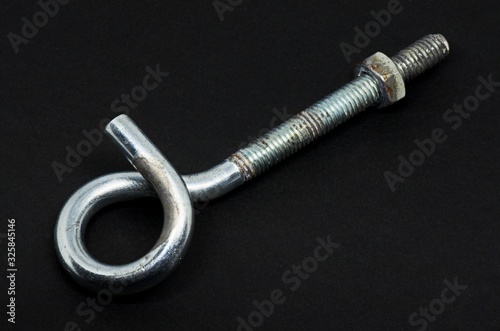 Steel pigtail screw hook on black background. Safety piece of hardware.