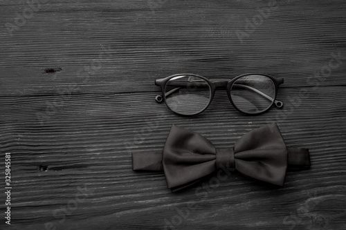 Stylish hipster fashion concept in minimal style. Trendy eyewear, bow tie black wooden grunge table