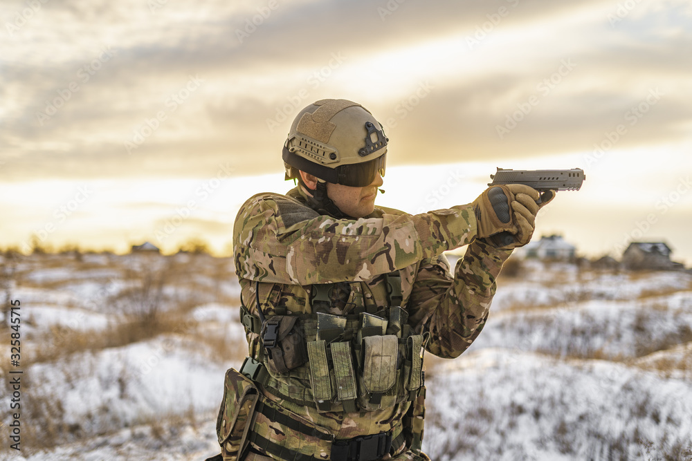 Modern war soldier army Man in multicam camouflage stands and aiming aim with gun in winter field. full equipment commandos with helmet and weapon gun stands and shooting soldier. warfare Modern war soldier army Man in multicam camouflage stands and aiming aim with gun in winter field. full equipment commandos with helmet and weapon gun stands and shooting soldier. warfare
