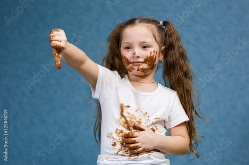 little girl eats chocolate and smudges her white t-shirt  face and hands him
