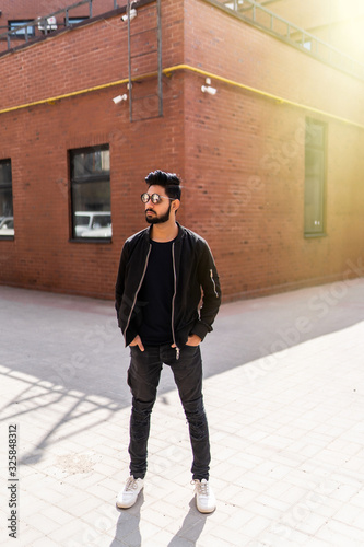 Handsome young indian man in sunglasses standing on the street