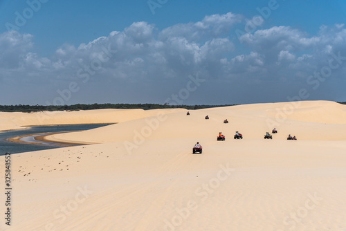 Group of friends riding quadricycles on white sand dunes and lagoons photo