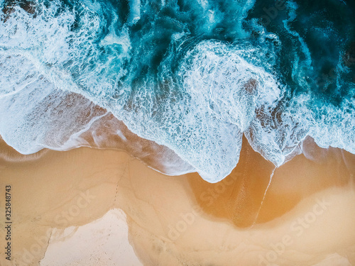 drone aerial view of ocean surf crashing on empty beach blue photo