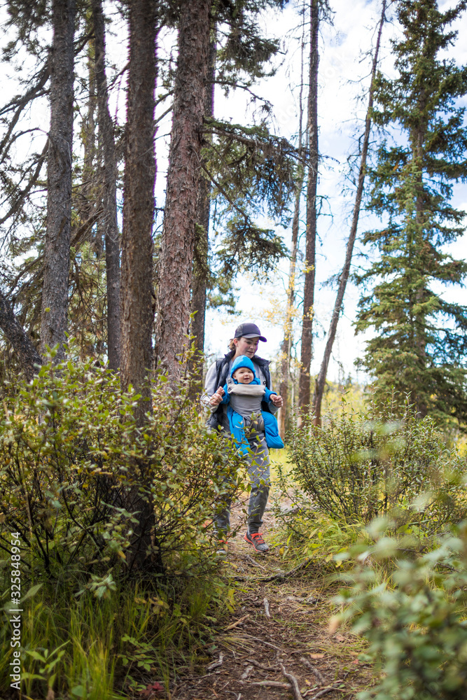 Mother walking through forest with baby in front carrier. Mother walking through forest with baby in front carrier.