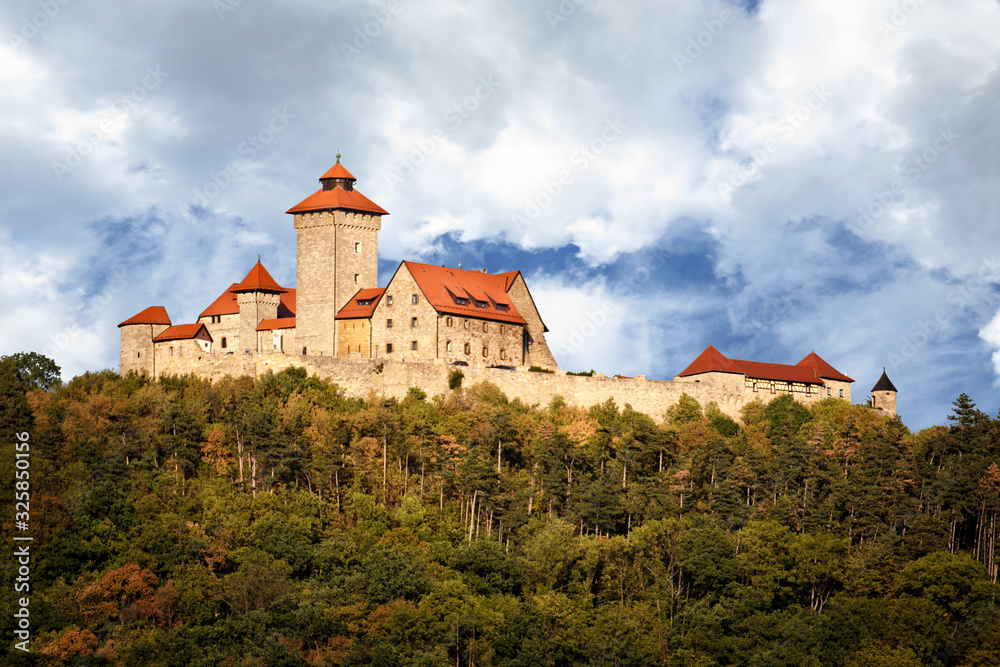 Panoramic photo of the castle called: Veste Wachsenburg in Thuringia. View of the entire castle in the countryside with forest in the foreground and blue sky