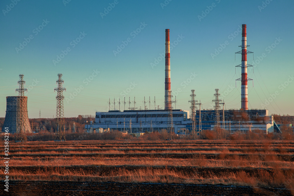 Thermal power station in a field illuminated by the rays of the setting sun Thermal power station in a field illuminated by the rays of the setting sun