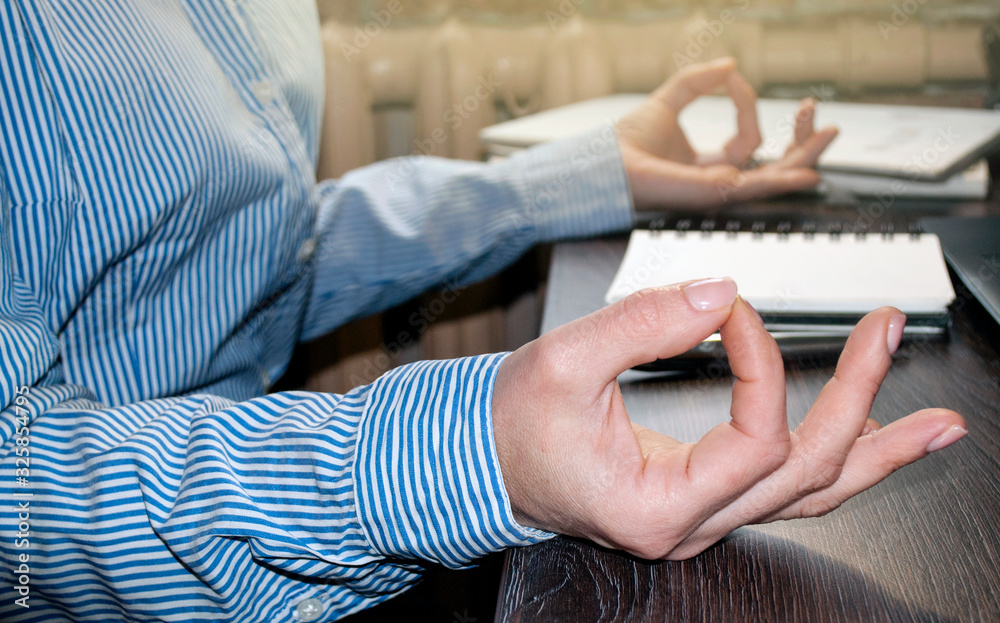 Fototapeta premium Office meditation to reduce work stress relieving concept, female hands in mudra close look, business woman practicing yoga in the workplace for development awareness. mental health and balance. Close