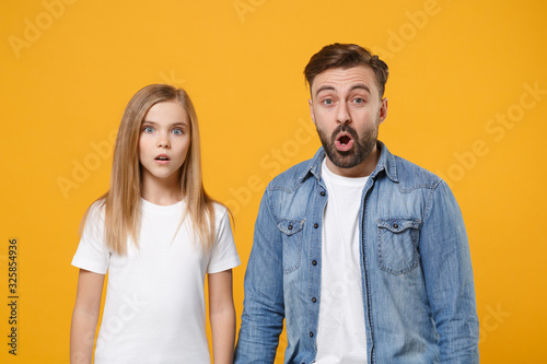 Shocked bearded man in casual clothes have fun with child baby girl. Father, little kid daughter isolated on yellow orange background. Love family day parenthood childhood concept. Keeping mouth open.