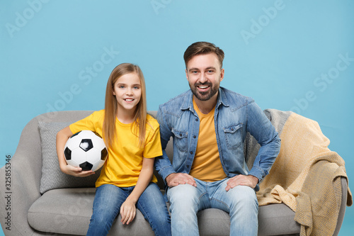 Smiling bearded man with cute child baby girl. Father little kid daughter isolated on pastel blue background. Love family parenthood childhood concept. Cheer up support favorite team with soccer ball.